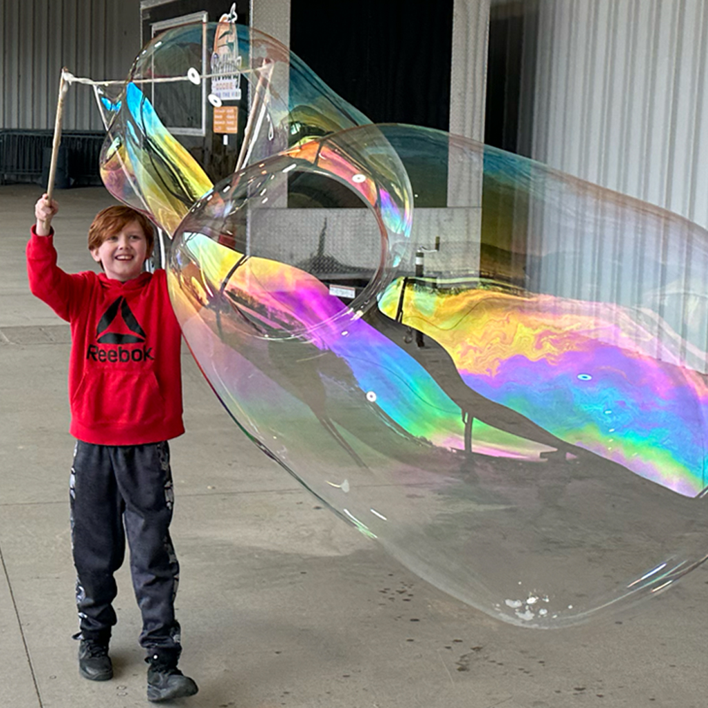 Original photograph of a child making a giant bubble outdoors